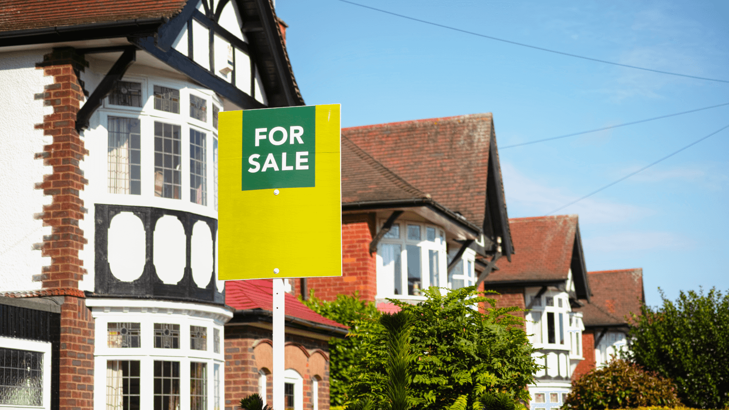 mock tudor houses with an estate agent's for sale sign in front of them