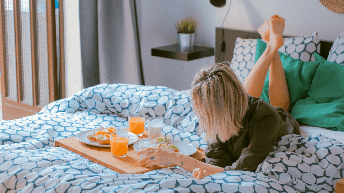 woman in bed with breakfast in bed including a glass of orange juice and eggs