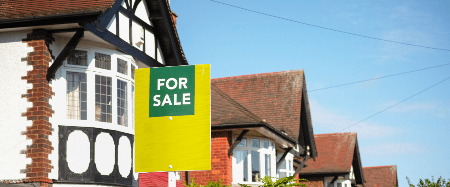 mock tudor houses with an estate agent's for sale sign in front of them