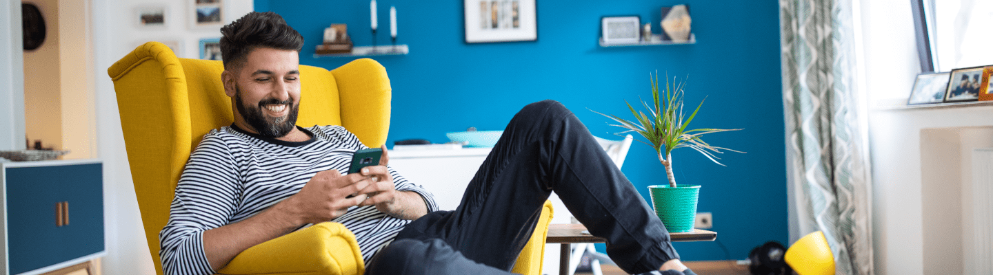 man slouched on armchair checking his phone