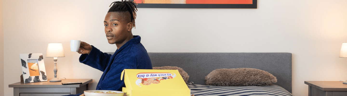 man enjoys breakfast in bed with cereal