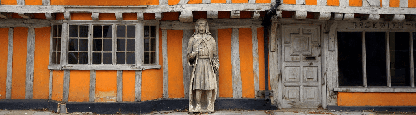 timber building that is painted orange with a statue in front of it