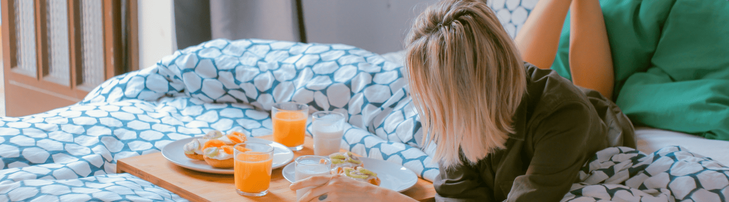 woman has breakfast whilst lying on her bed