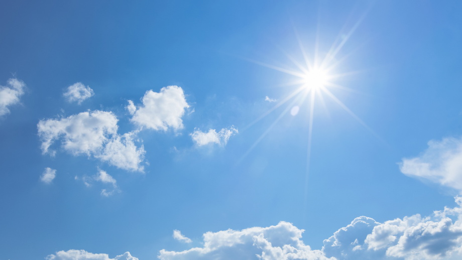 Blue sky with sun shining and a few small white clouds